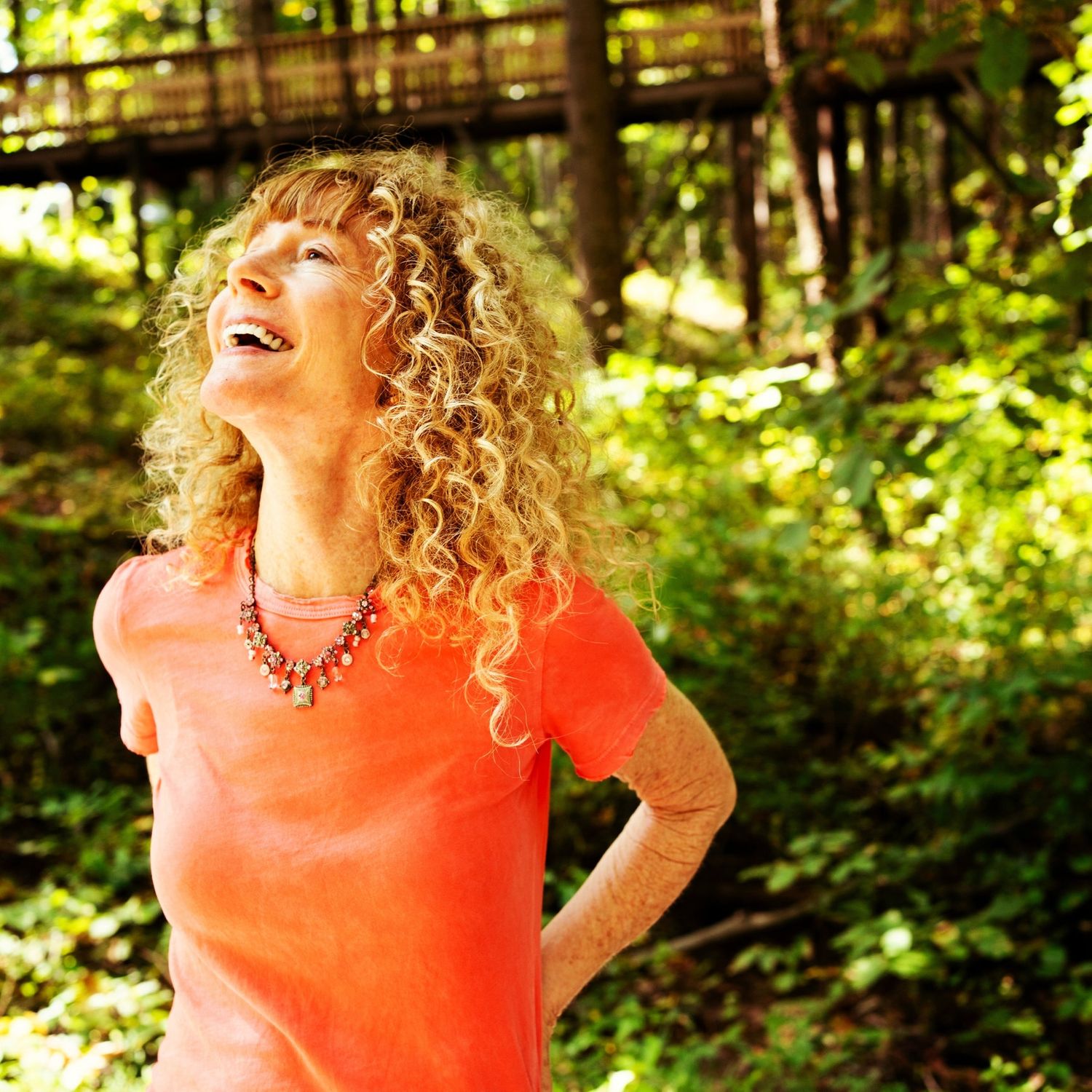 A photo of a red head woman laughing a lot and looking up at the sky.