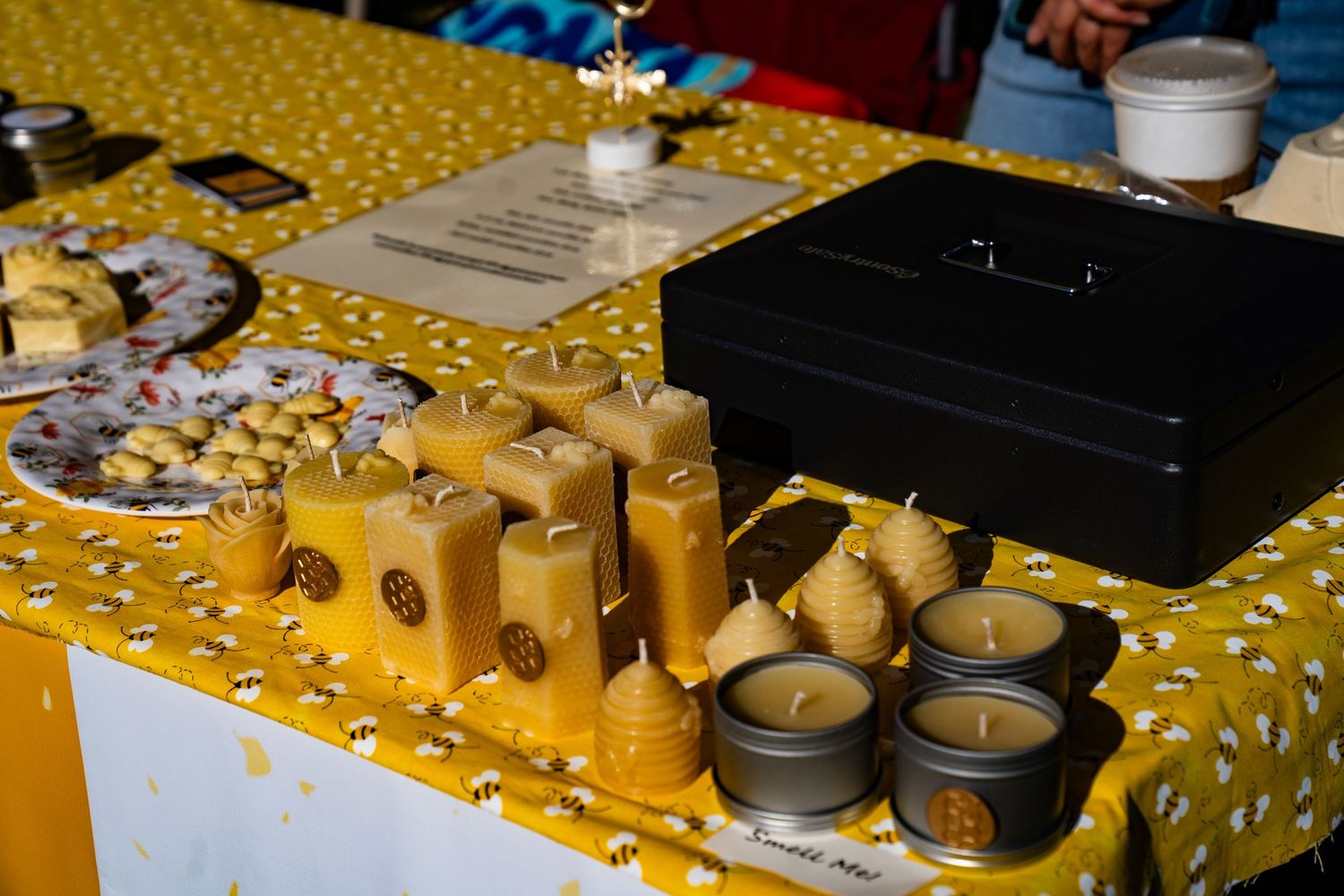 Hand-poured candles displayed on a table at the Bee Yourself Honey booth at the farmers market.
