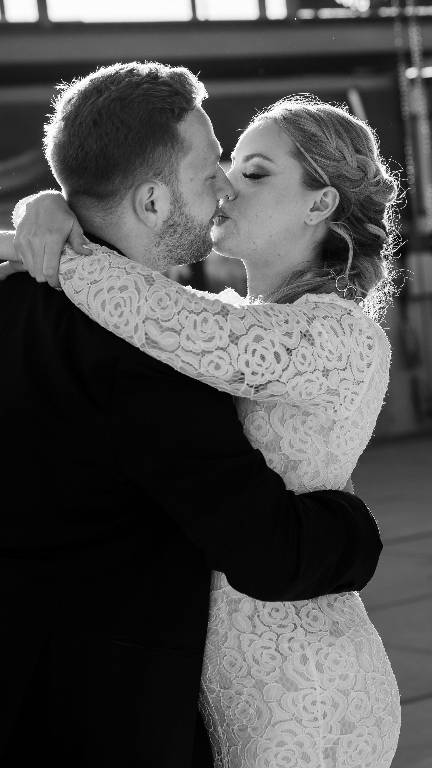 Black and white photo of a bride and groom sharing a romantic kiss during their wedding first dance.