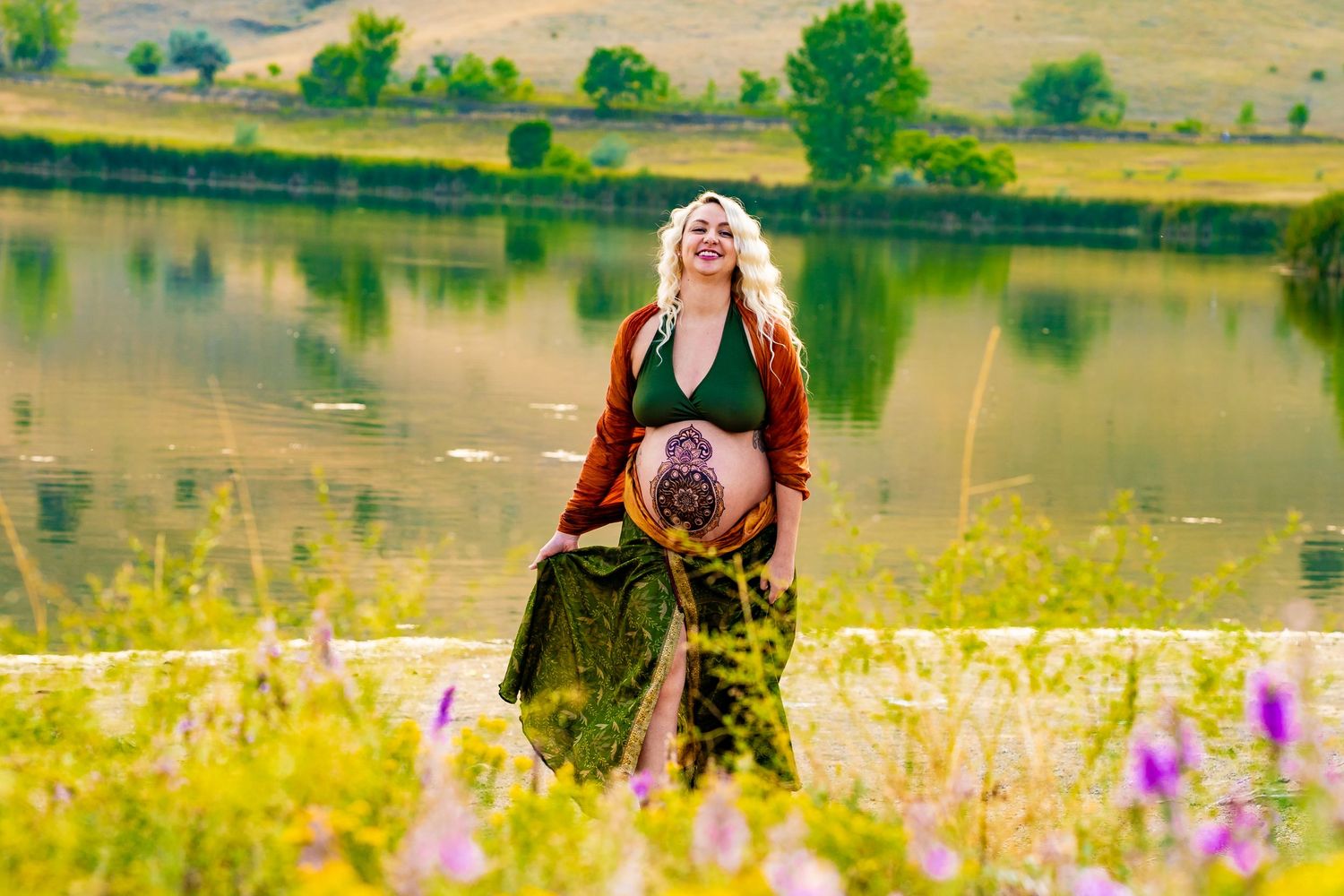Scenic field of yellow wildflowers blooming in front of a tranquil lake on a sunny summer day.