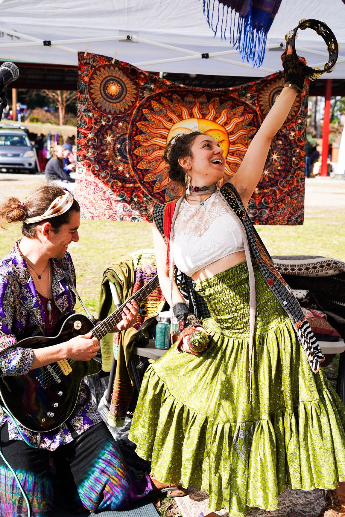 A woman wearing a green skirt and white top performs alongside a man in downtown Boulder, sharing music and smiles with the crowd.