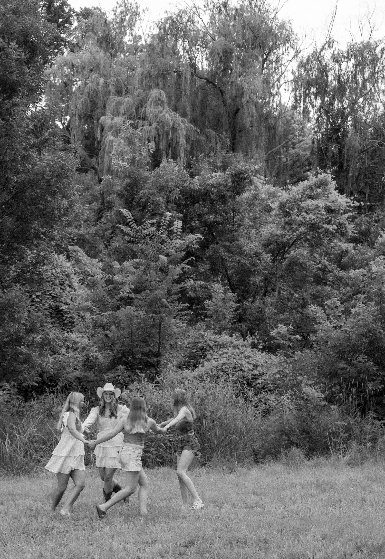 A sequence of black and white photos showing people running and playing in a grassy field with trees in the background.
