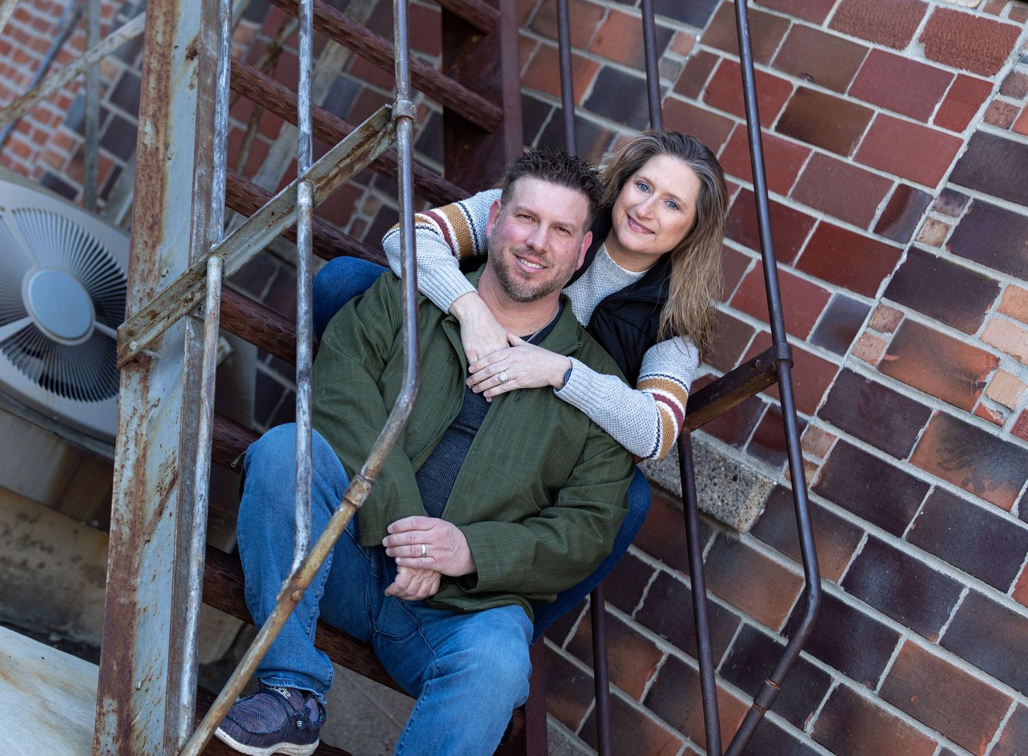 A couple sits together on brick steps outside a building in a series of candid poses.