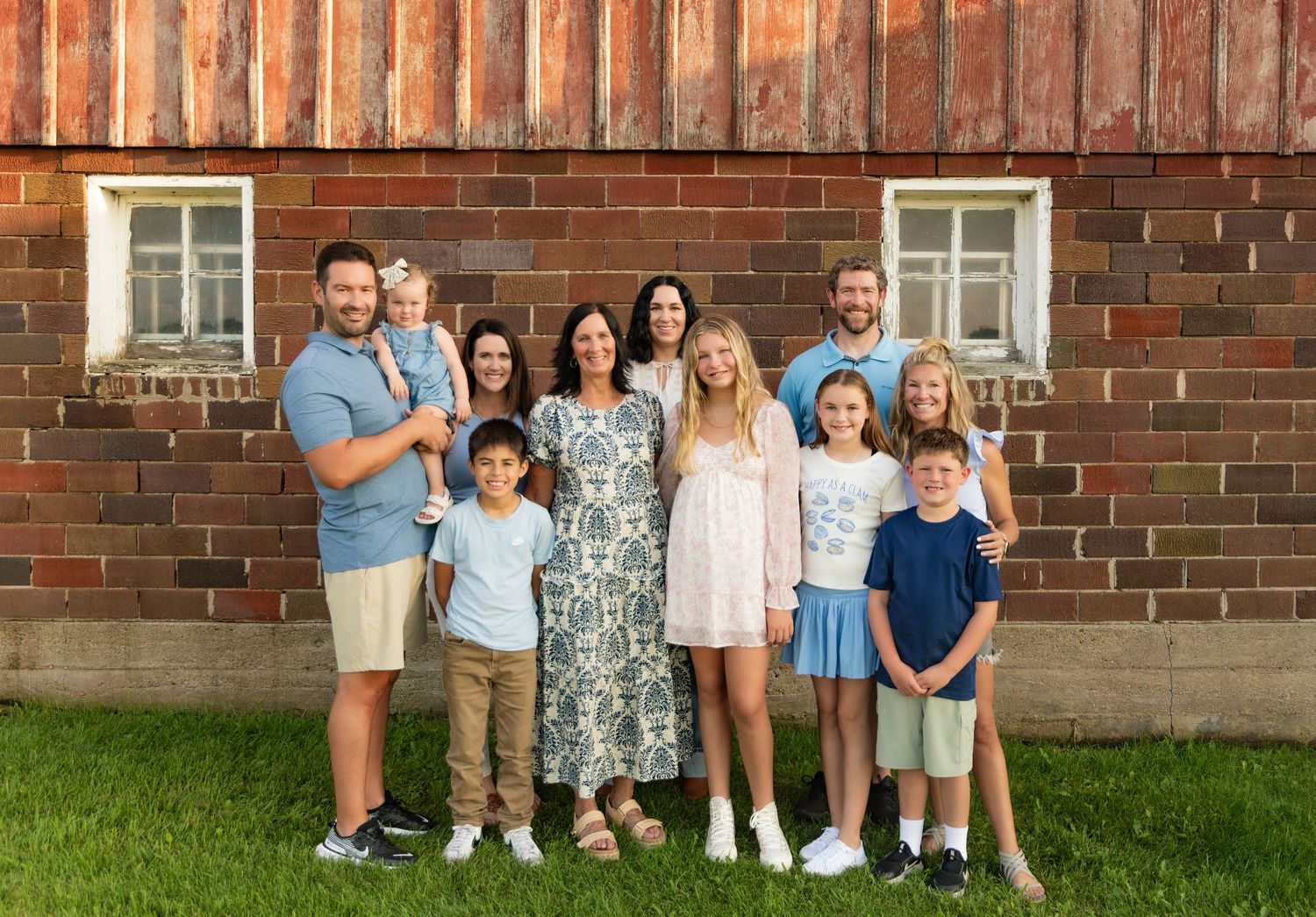 A group of people standing in front of a red brick building wearing casual summer attire.