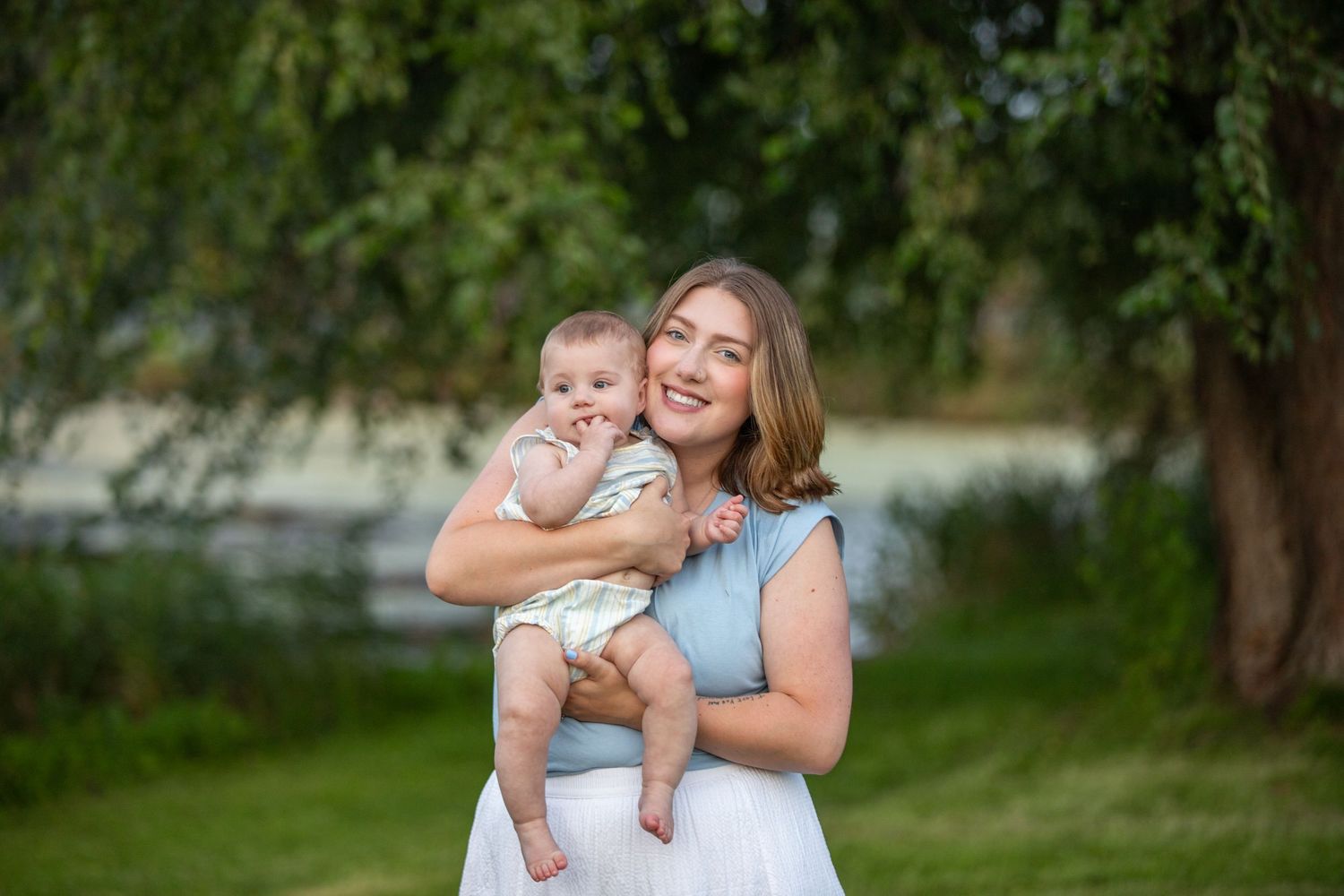 A mother and baby share joyful moments together in a lush outdoor garden setting.