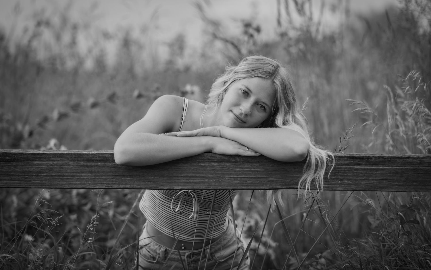 Black and white portrait series of a senior lying in a meadow at sunset.