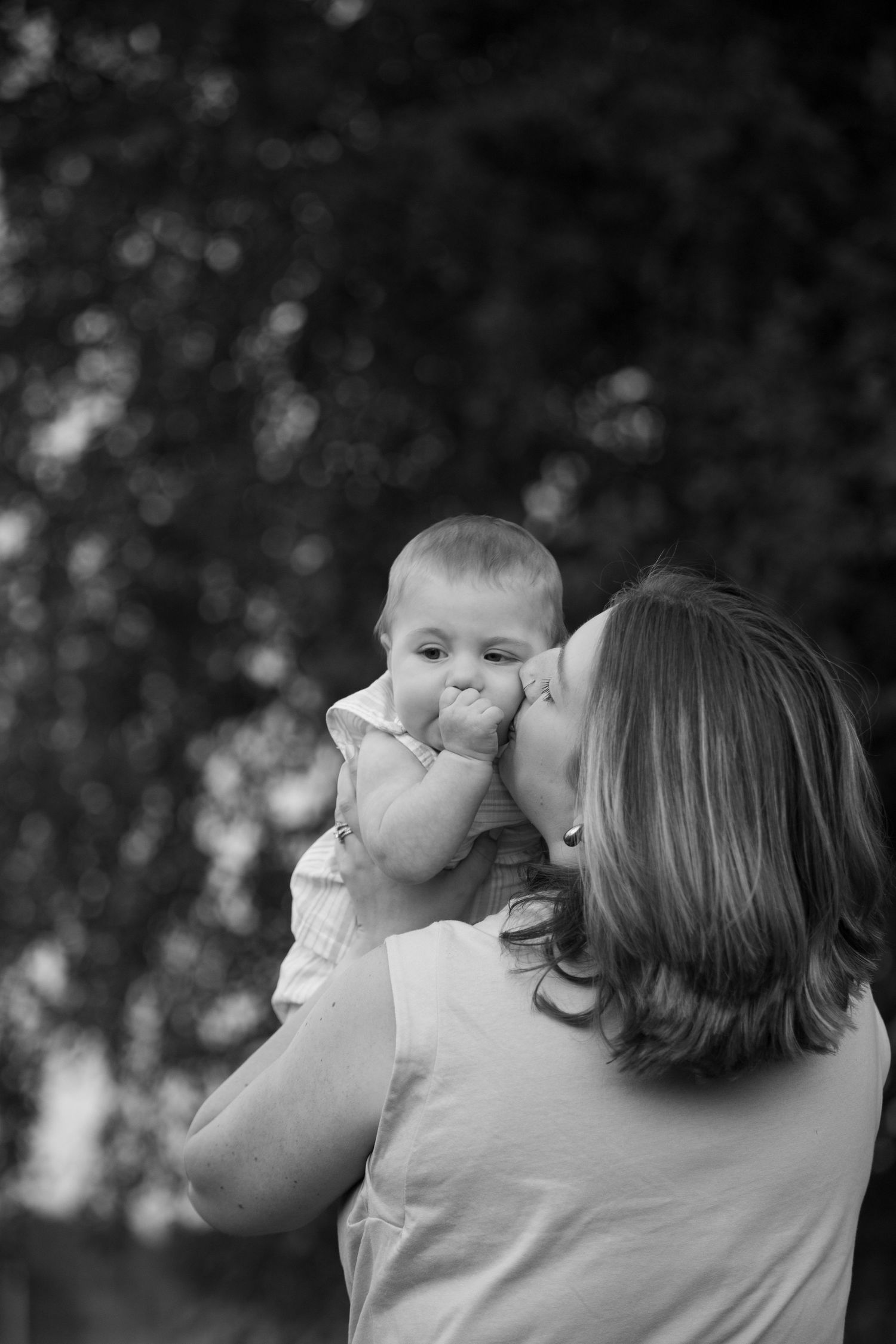 Black and white photo series showing a parent and child in a tender moment of affection outdoors.