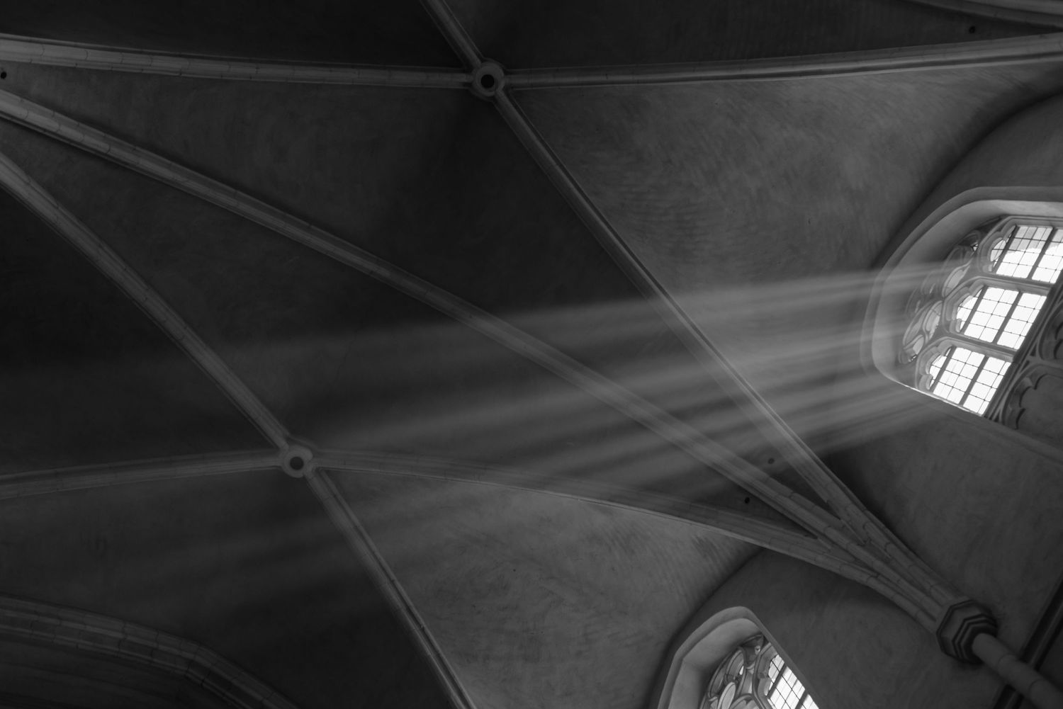 Dramatic beams of sunlight streaming through windows in a cathedral ceiling.