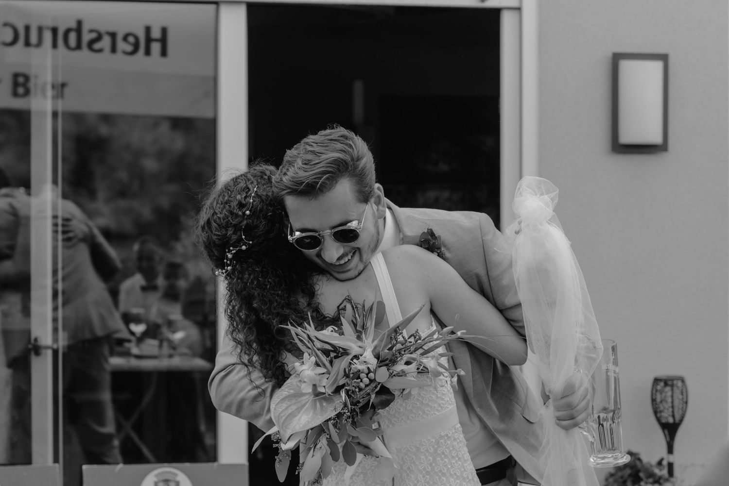 A joyful black and white wedding moment captured with a couple embracing and laughing together.