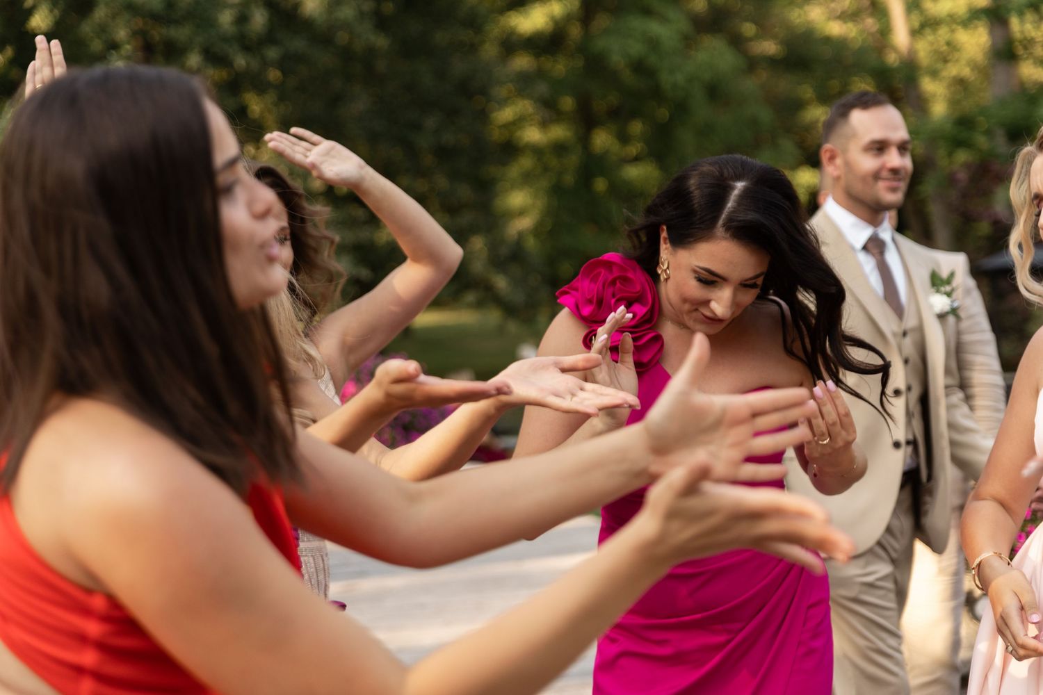 Wedding guests dance and celebrate together on an outdoor patio during a summer reception party.