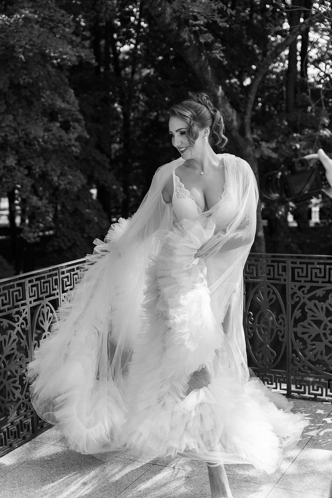 A bride in a flowing white wedding dress twirls gracefully in a series of black and white photographs outdoors.