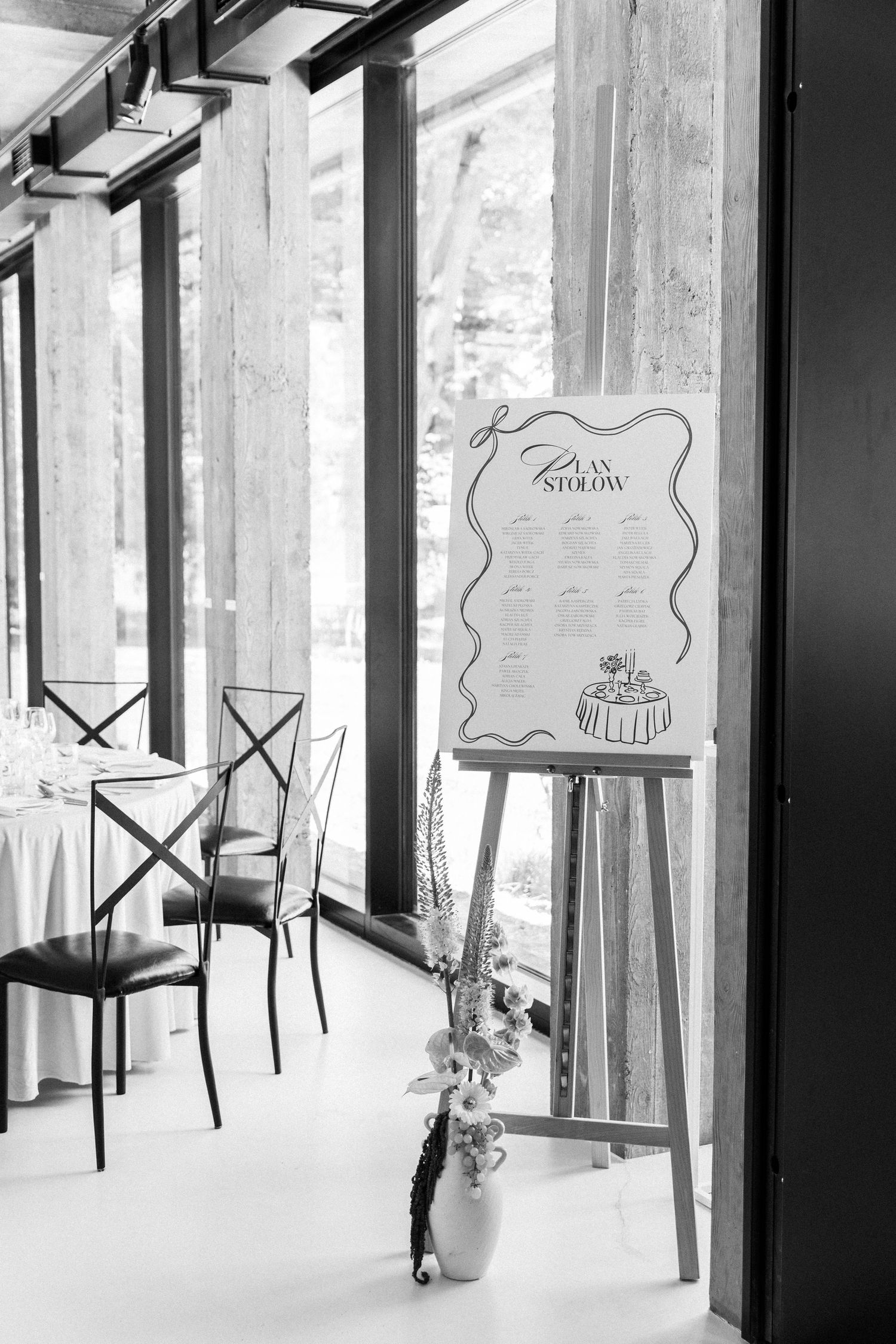 Black and white image of modern chairs arranged along window panels, creating a minimalist interior setting.