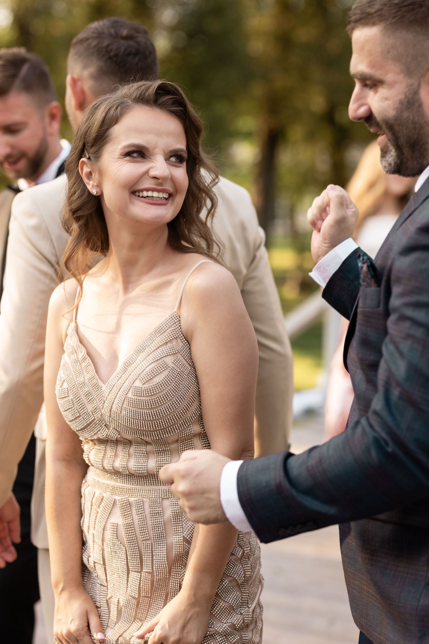 Guests share a joyful moment at an outdoor wedding celebration with people wearing formal attire.