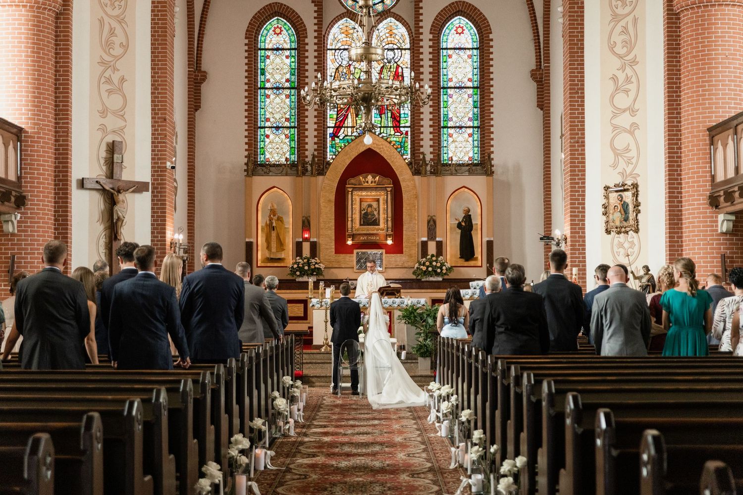 Panoramic view of a traditional church interior with stained glass windows, wooden pews, and ornate architectural details.