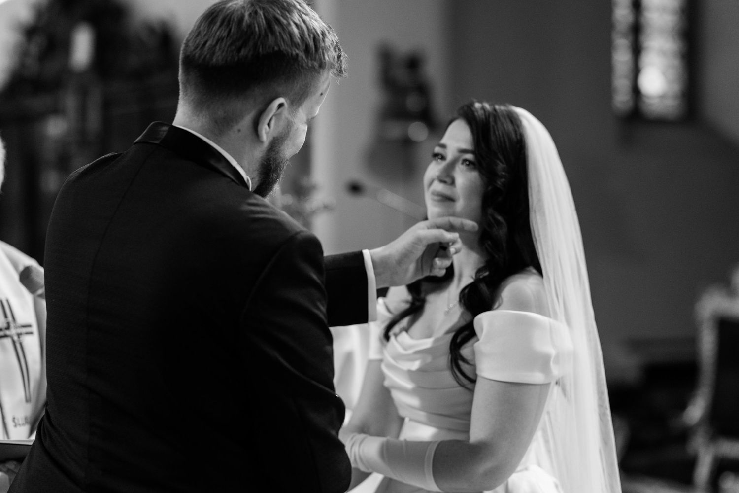 An intimate black and white moment captured between a bride and groom during their wedding ceremony at a church.