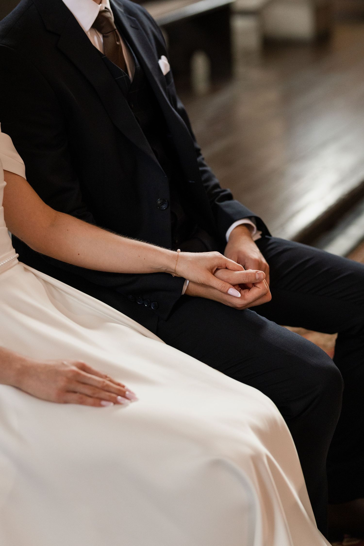 Close-up of hands resting on a white wedding dress fabric creating elegant folds and texture.