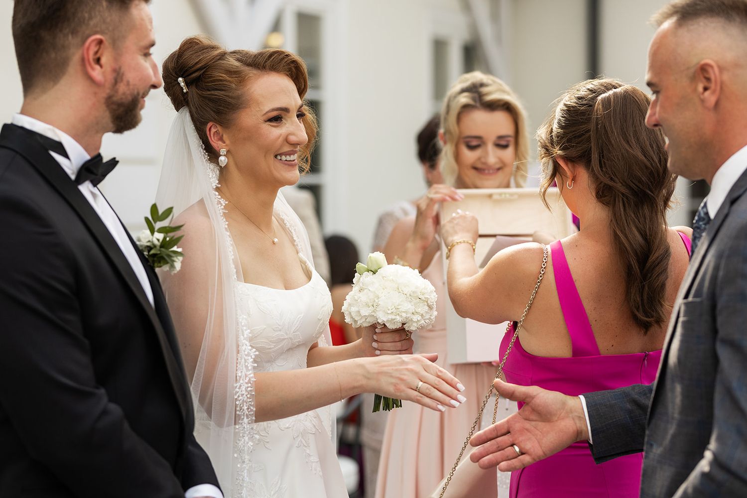 Wedding guests gather in formal attire for a celebratory moment at an indoor reception.