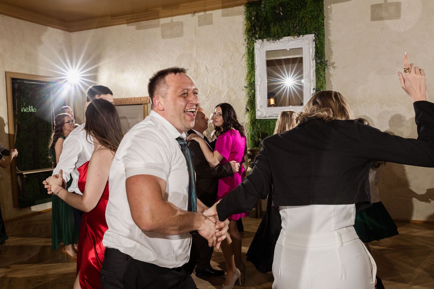 Lively dance party at a wedding reception with party guests dancing and having fun on the dance floor.