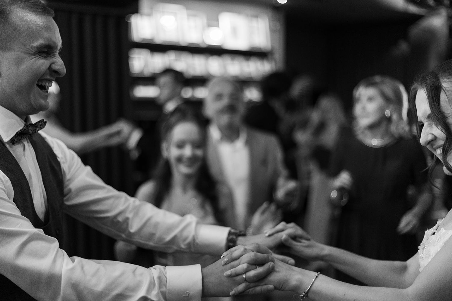Black and white image of people dancing and celebrating at a lively social gathering.
