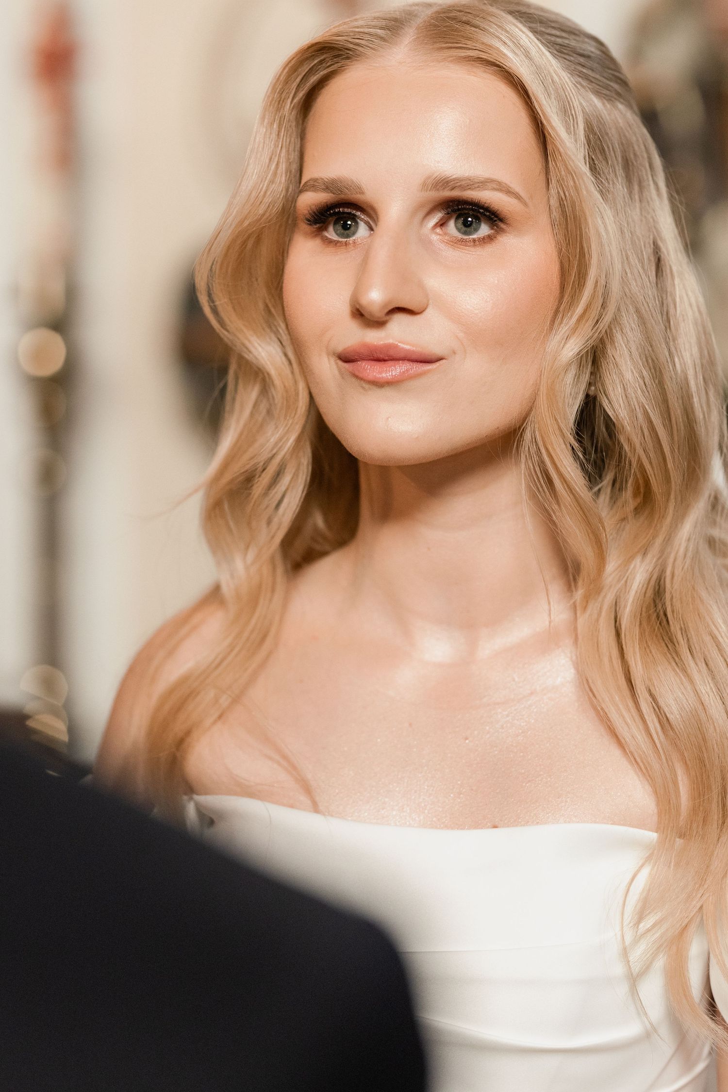 Close-up portrait of a bride with wavy blonde hair wearing a white strapless dress.
