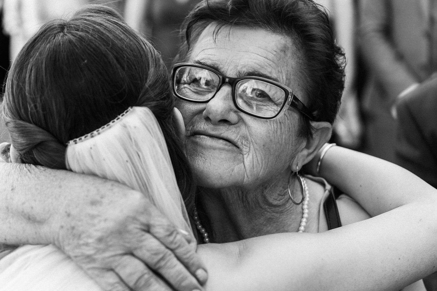 Black and white photograph showing a tender emotional embrace between people, captured in intimate detail.