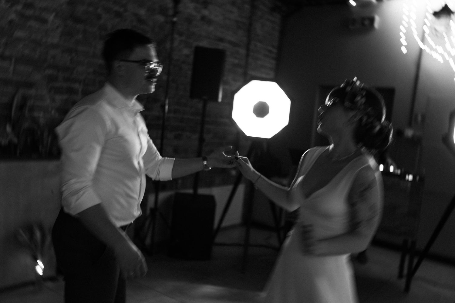 A couple sharing a dance in monochrome lighting at a wedding reception, with the circular light creating a dramatic effect.