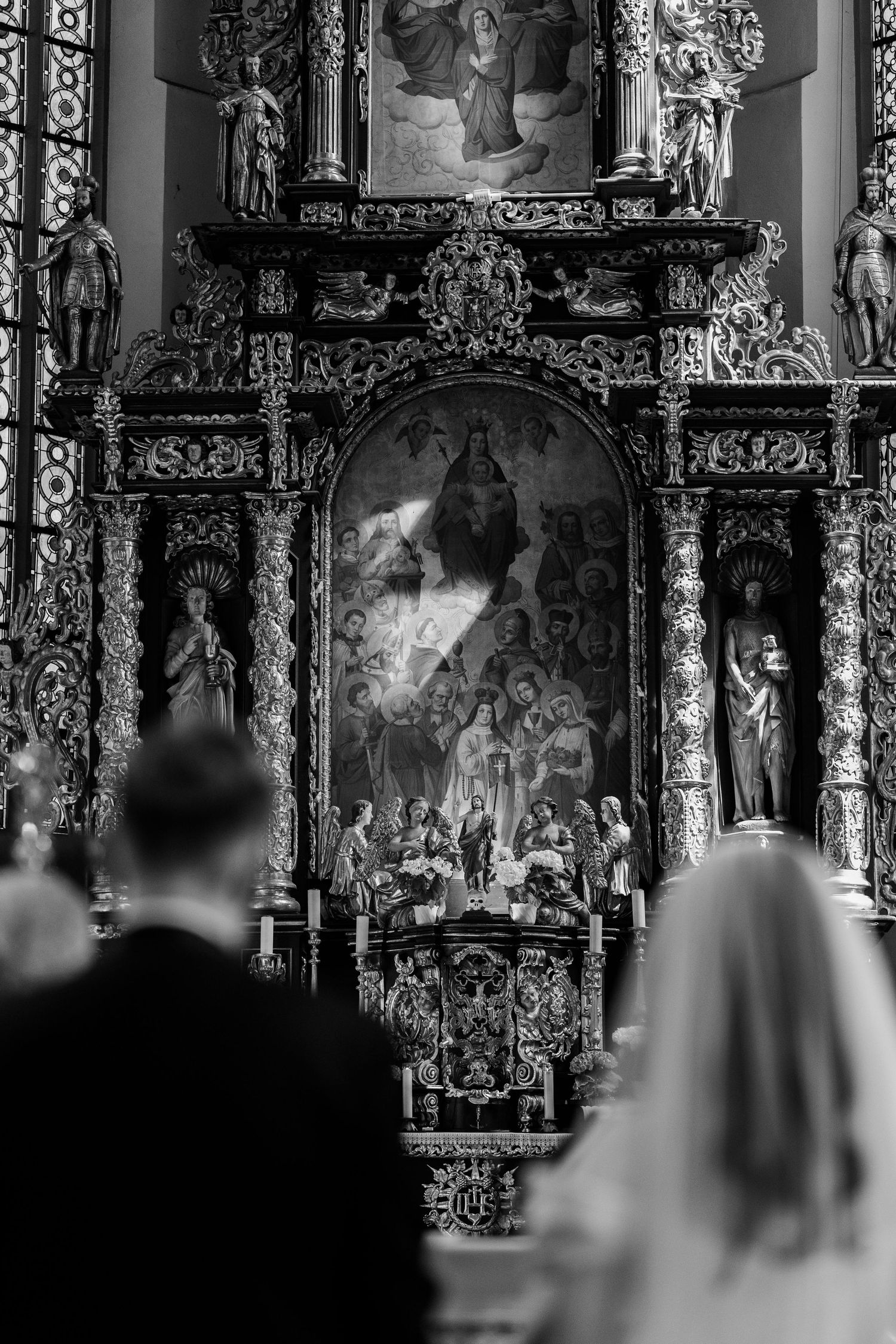 Black and white photo of ornate Catholic church altar with elaborate Baroque religious artwork during wedding ceremony.