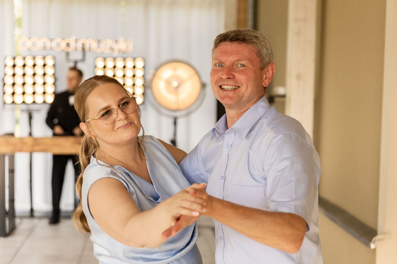 Two people dancing together in a warm-lit room, showcasing a graceful dance move.