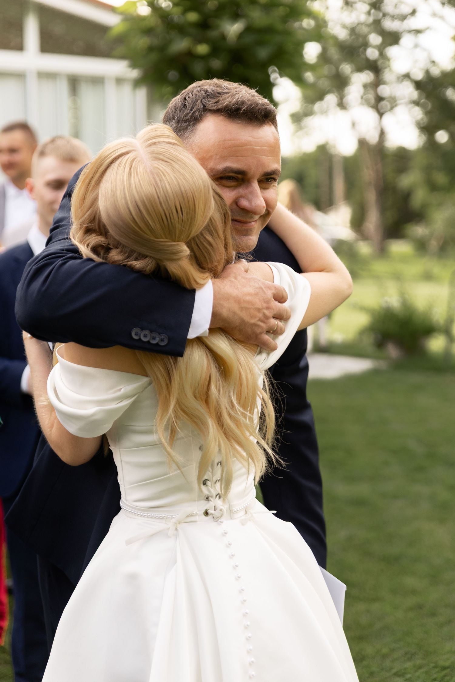 A couple shares an intimate dance moment outdoors at a wedding celebration in a garden setting.