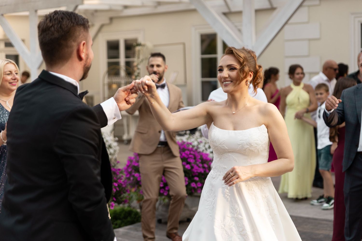 Newlywed couple shares a romantic dance at their wedding reception while guests watch and celebrate.