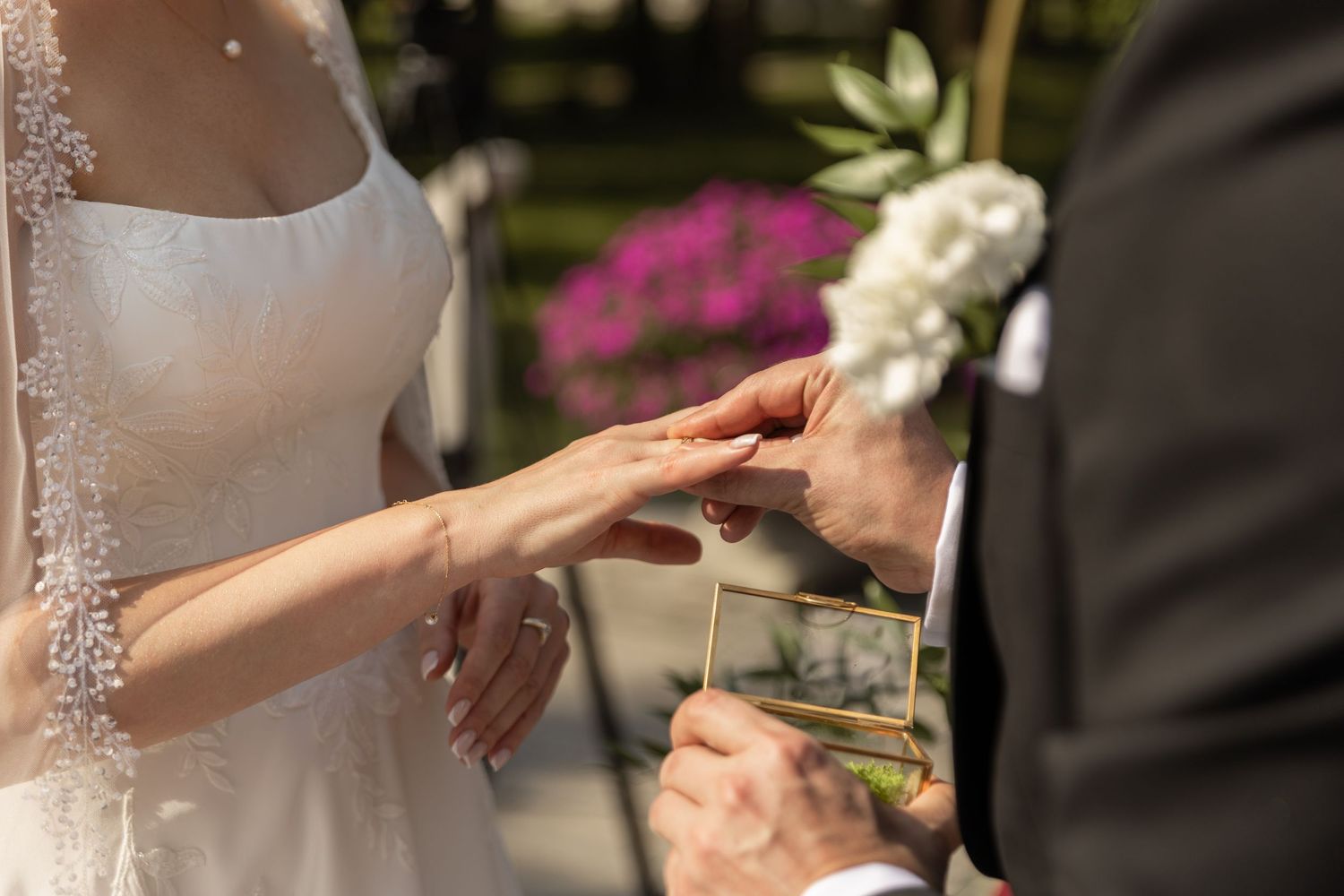 Close-up shots of wedding rings being exchanged during an outdoor ceremony with natural lighting.