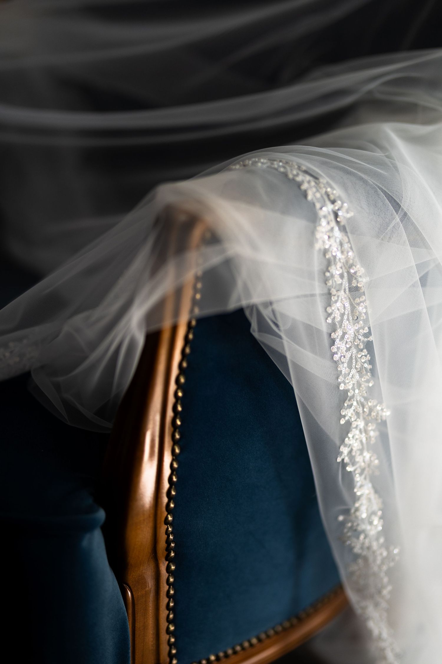 A flowing white bridal veil with delicate lace trim cascades elegantly against a dark blue background.