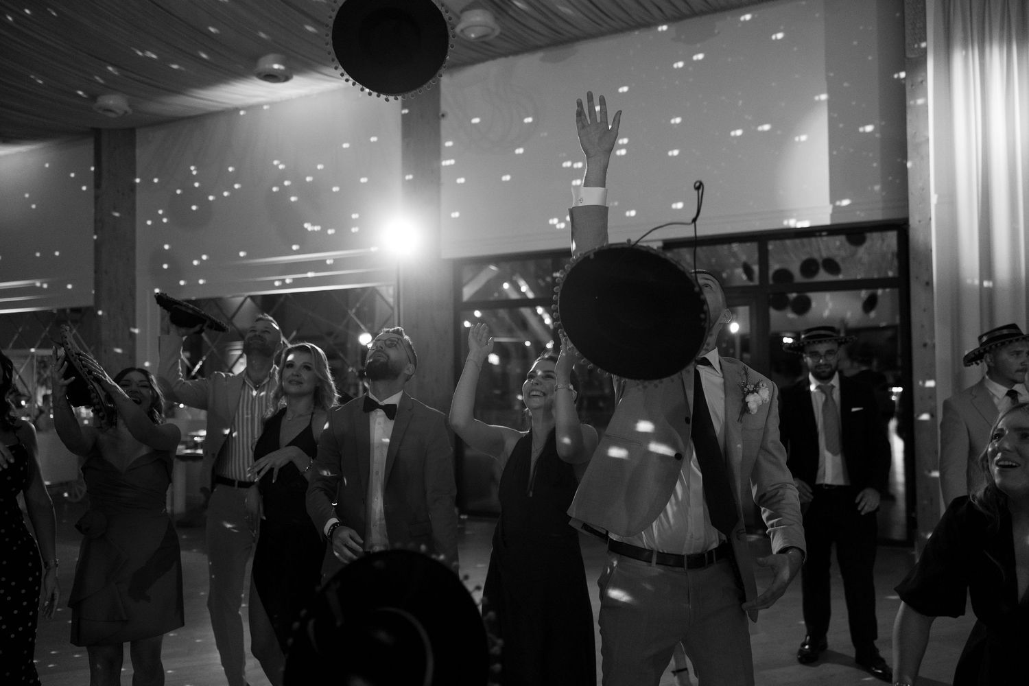 Black and white photo of wedding guests dancing and celebrating on the dance floor at a festive reception.