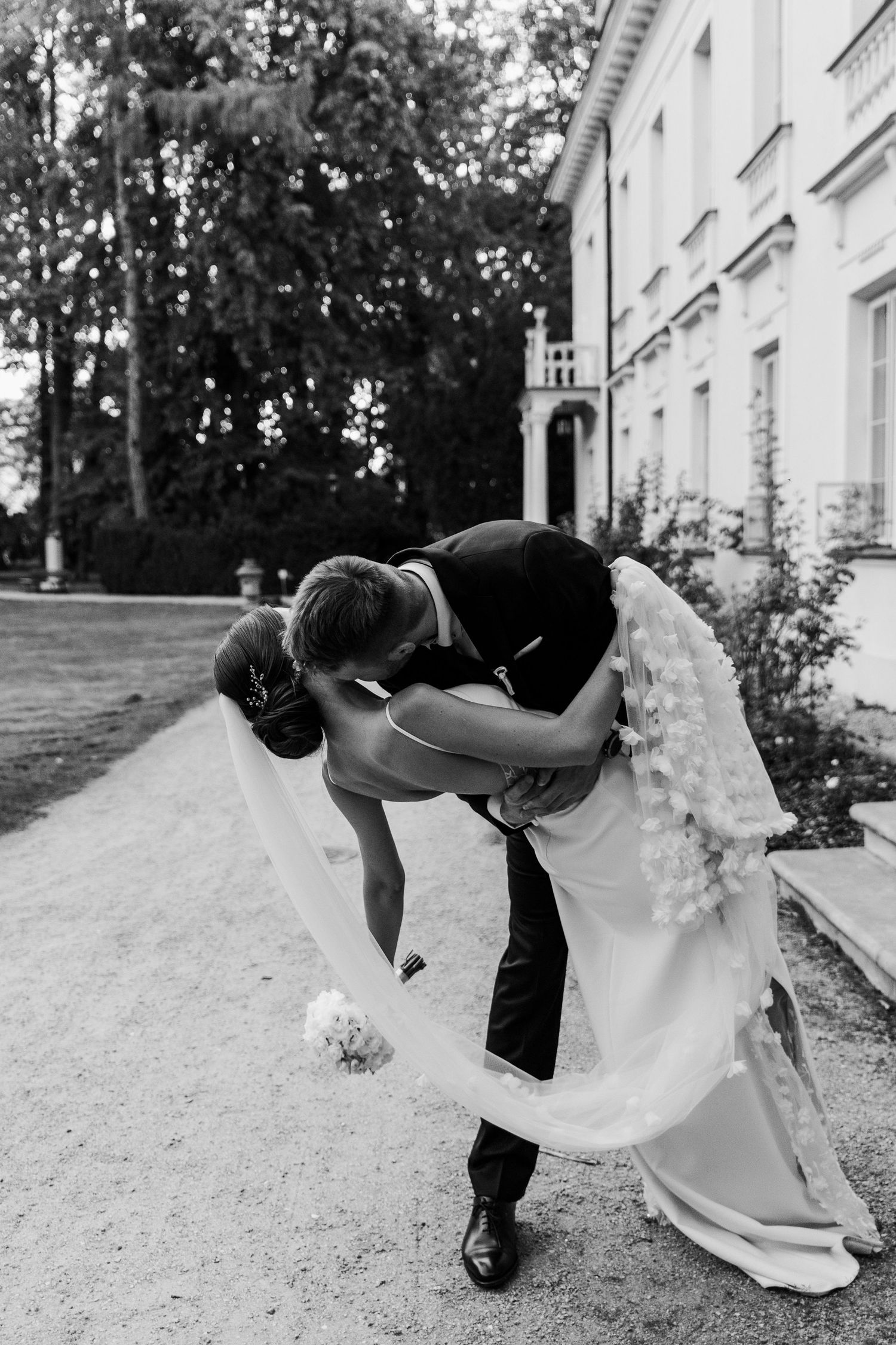 Dramatic black and white wedding photo of romantic dip kiss in front of historic building.