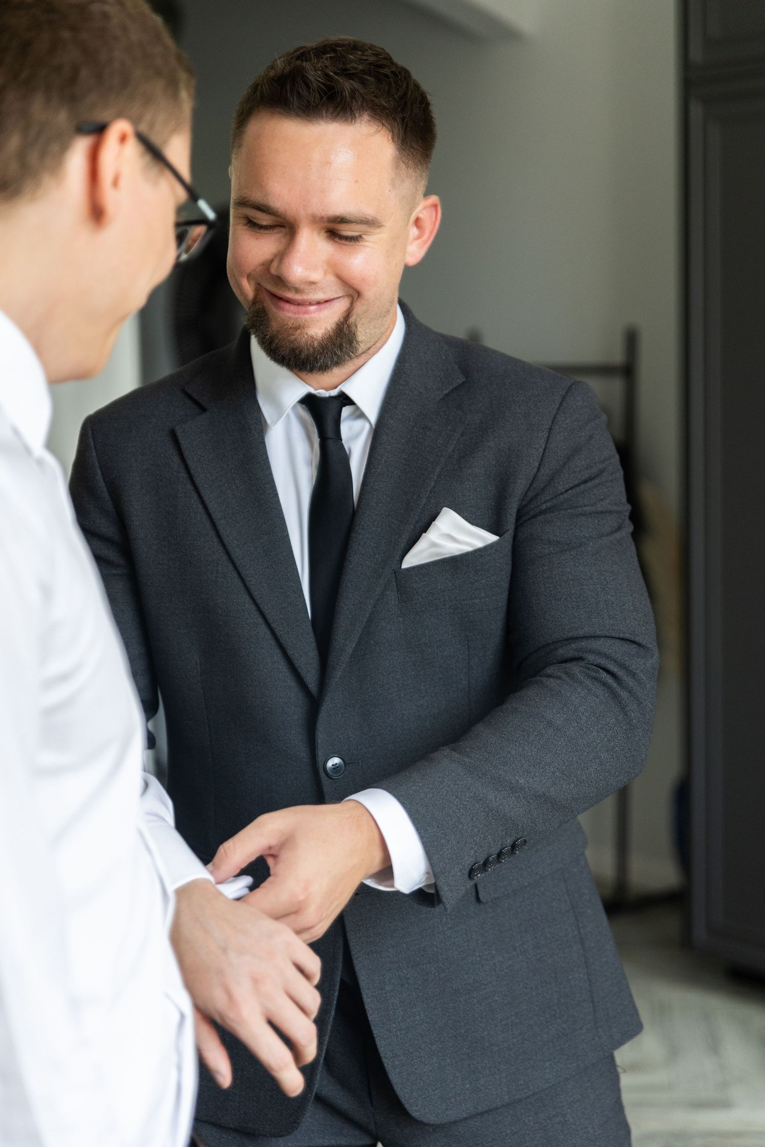 Professional in dark suit and white pocket square smiles warmly during a business conversation.
