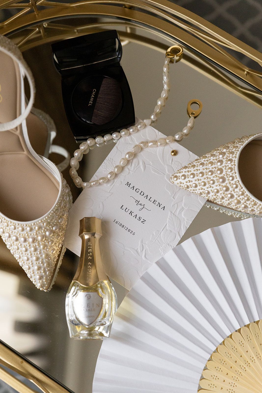 Pearl necklace and white paper fan displayed on gold hanger with elegant product tags.