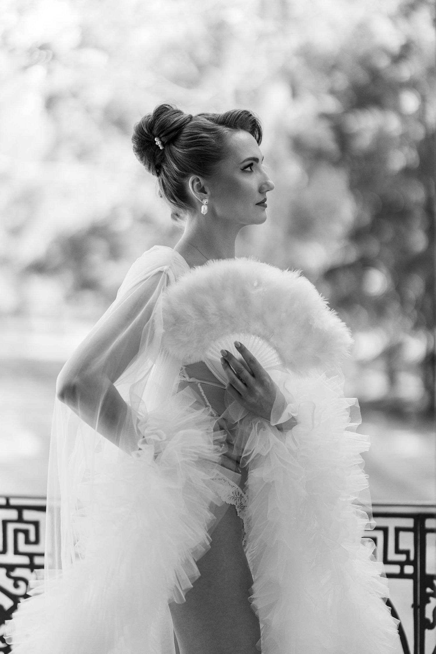 A black and white photo series shows a woman in an elegant dress with dramatic white feather angel wings posing outdoors.