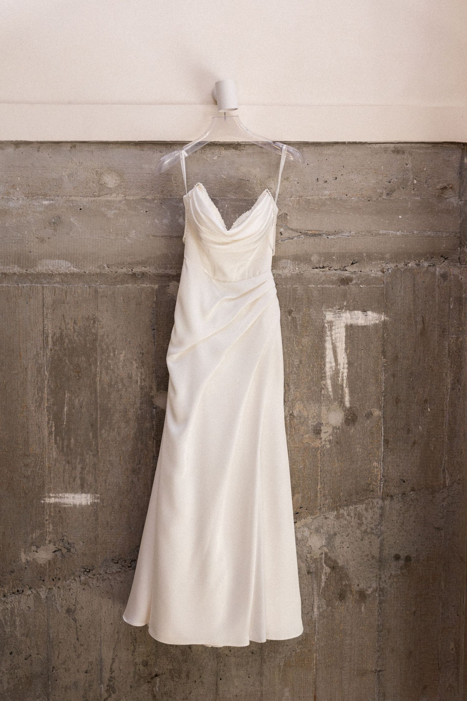 A sequence of white formal dresses displayed against a concrete wall showing different angles of the same garment.