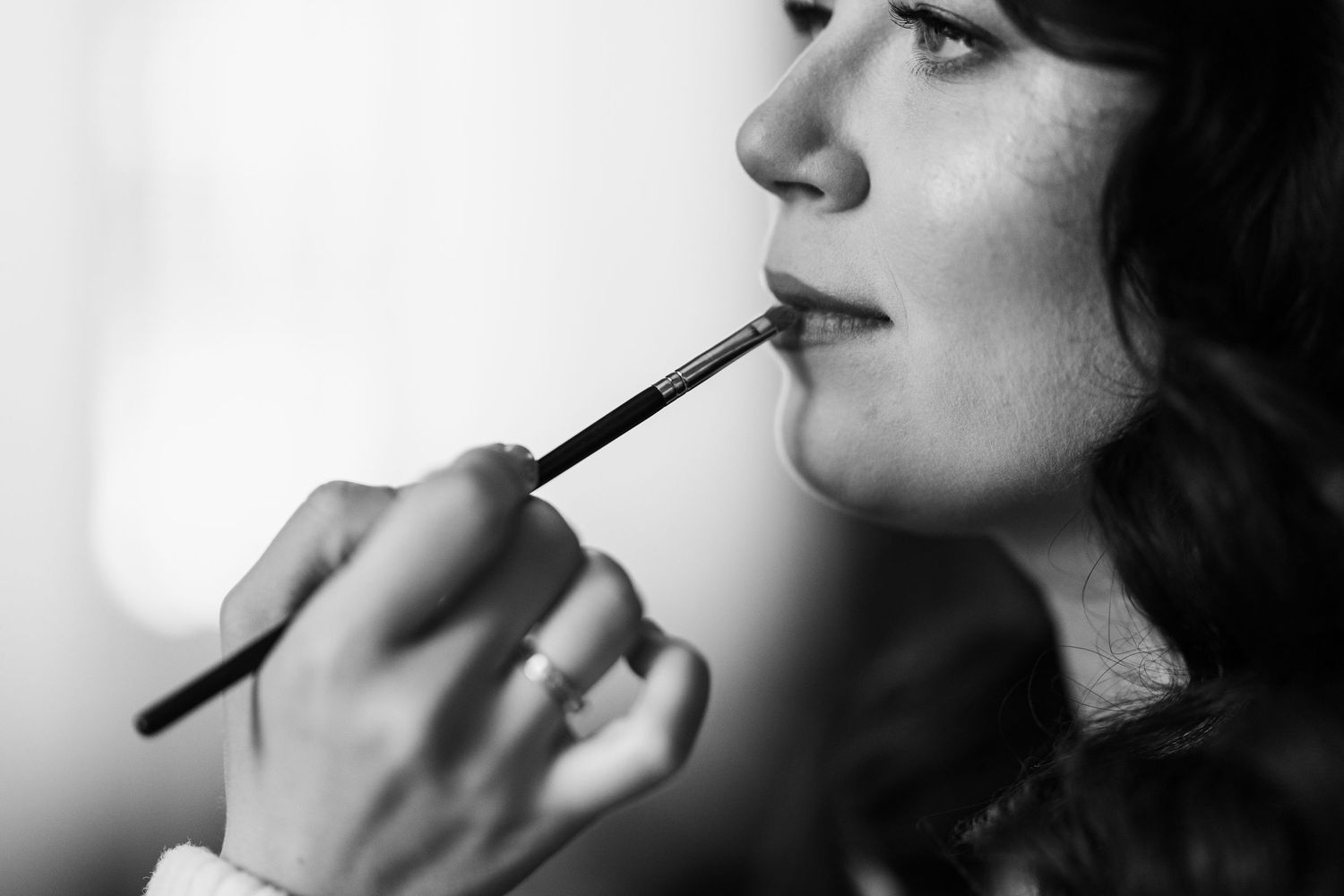 Black and white beauty shot of makeup application with a brush, captured in artistic profile view.