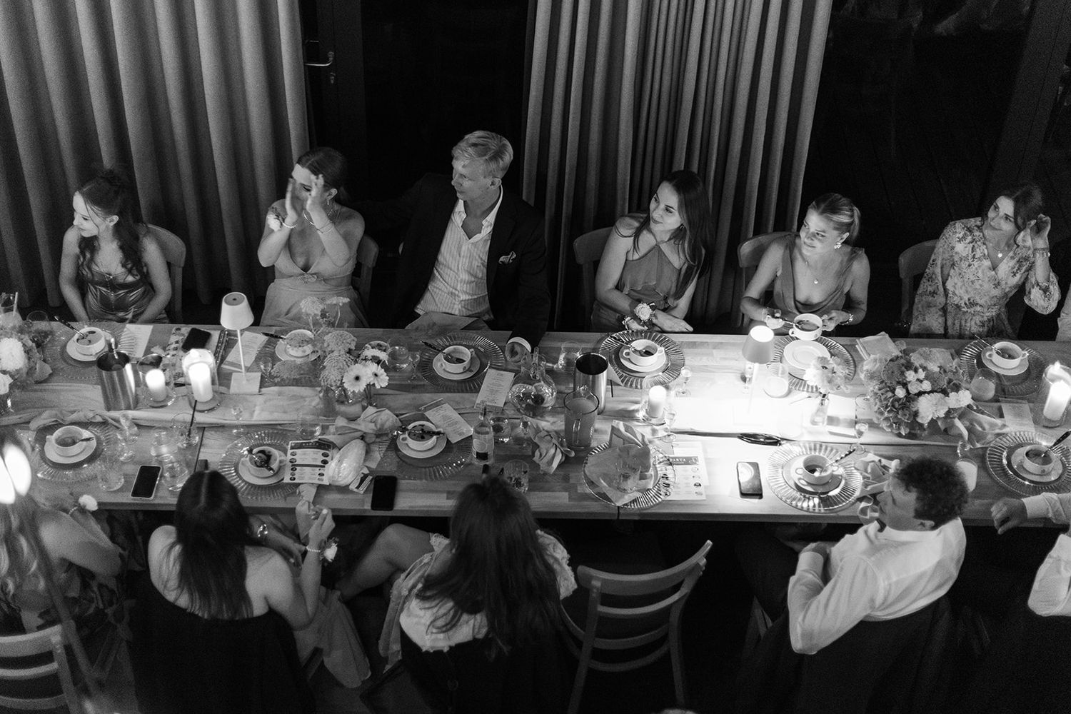 Black and white photo showing people seated at long dining tables in a formal banquet setting.