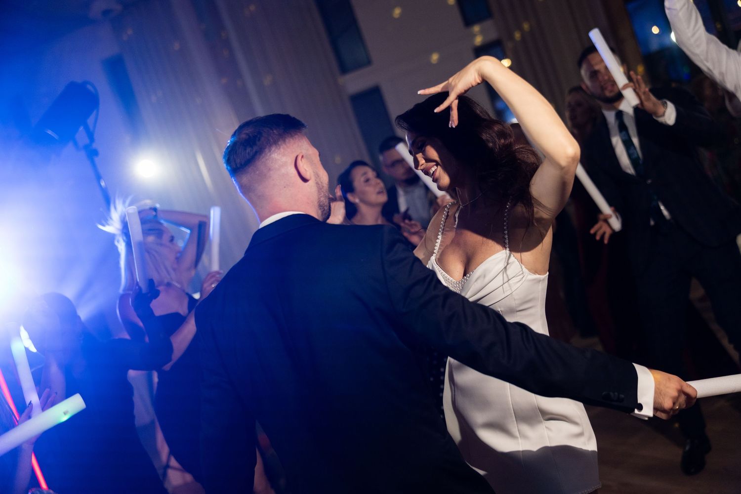 Bride and groom share a joyful first dance surrounded by guests at an elegant wedding reception.
