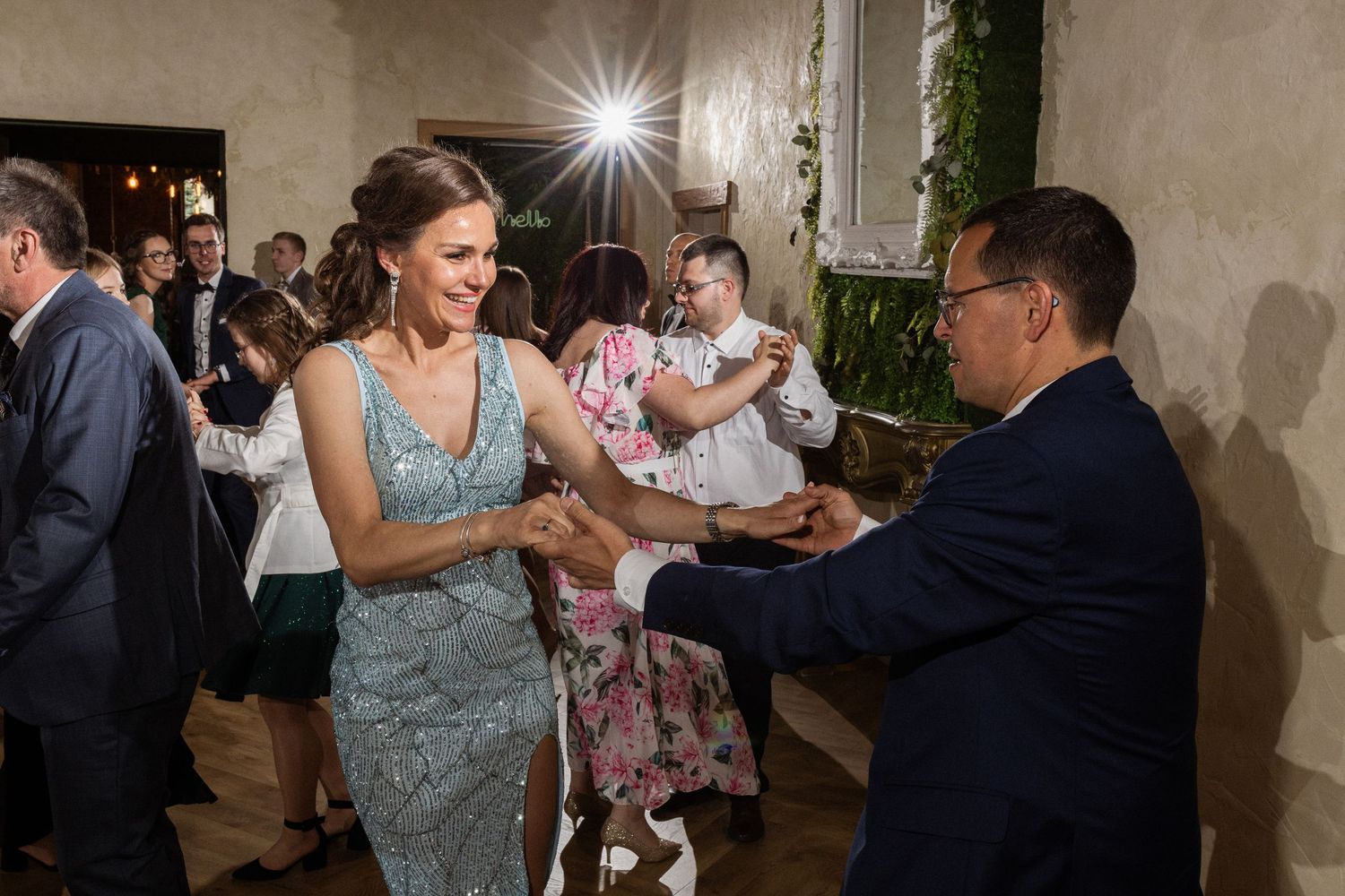 Guests dancing and socializing at an elegant evening reception in a neutral-toned venue with soft lighting.