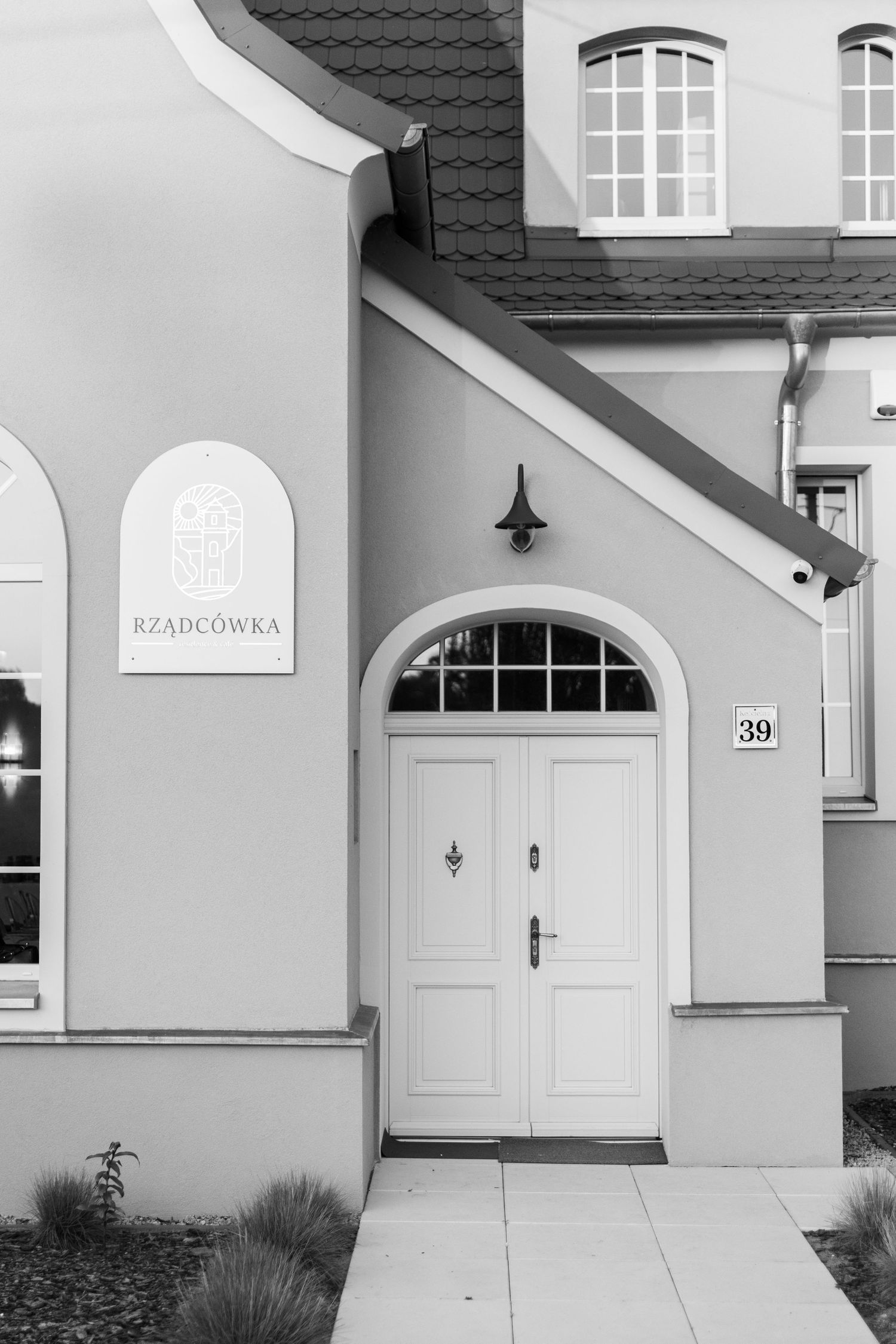 Minimalist architectural details of white residential buildings with arched doorways and black tiled roofs.
