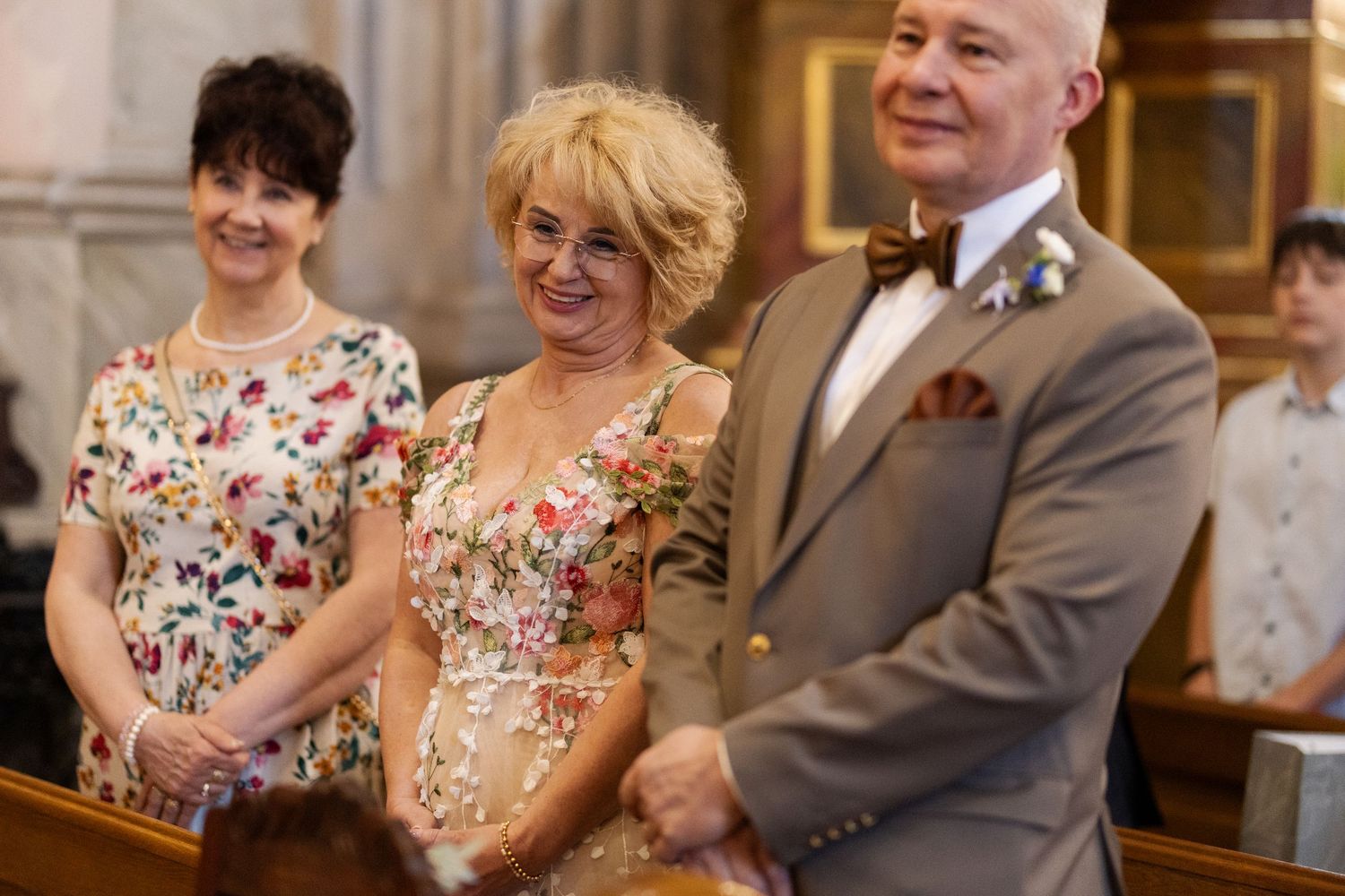 Guests share a joyful moment during a wedding ceremony inside an ornate church.