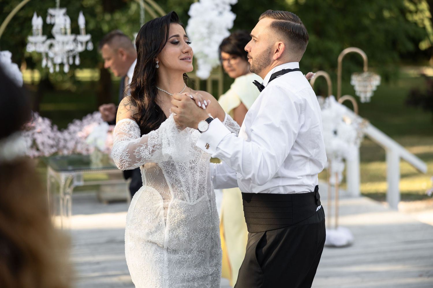 Bride and groom share a first dance outdoors at an elegant wedding ceremony with white floral decorations.