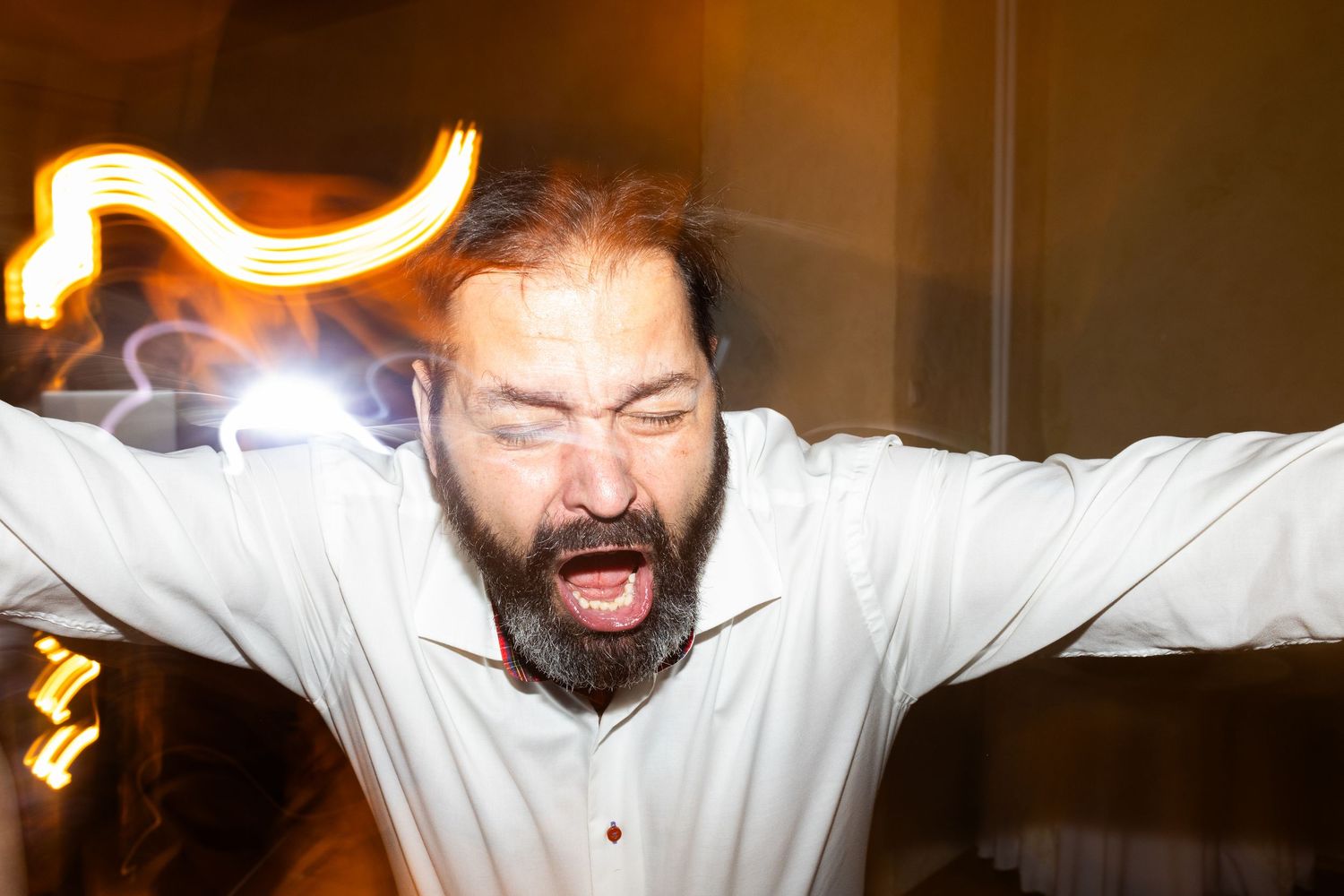 Person in white shirt captured in motion with blurred light trails and mouth open in expressive pose.