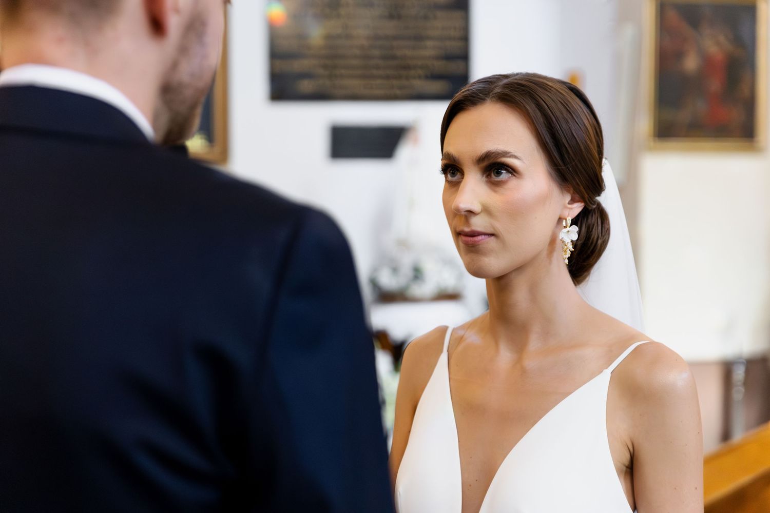 A couple exchanges wedding vows inside an elegantly decorated ceremony space with artwork on the walls.
