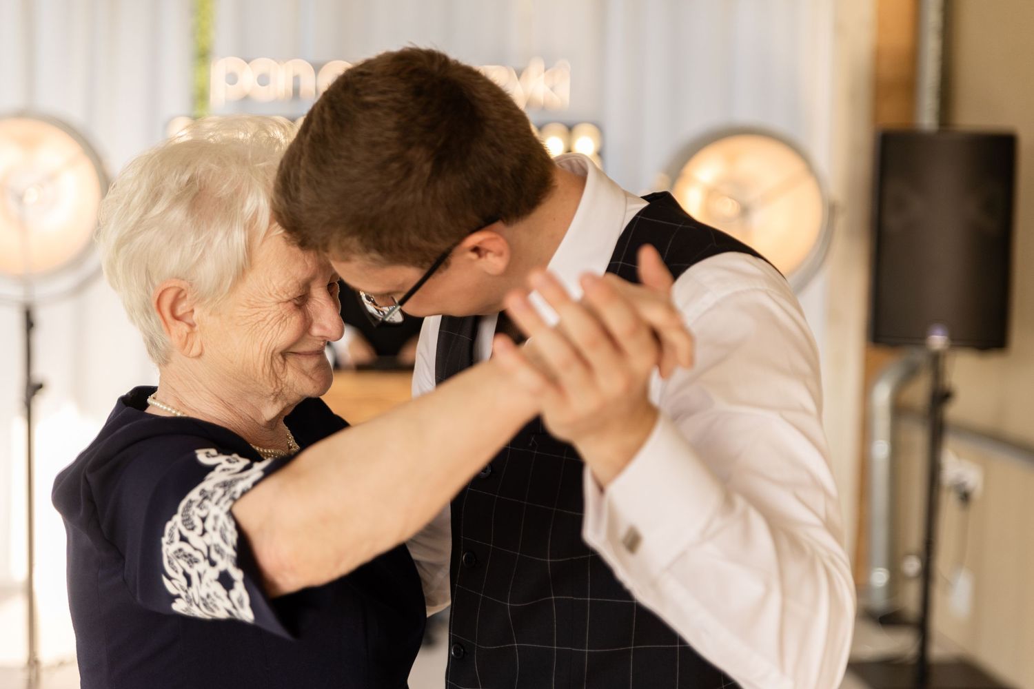 Two people share a tender dance moment together in an intimate indoor setting.
