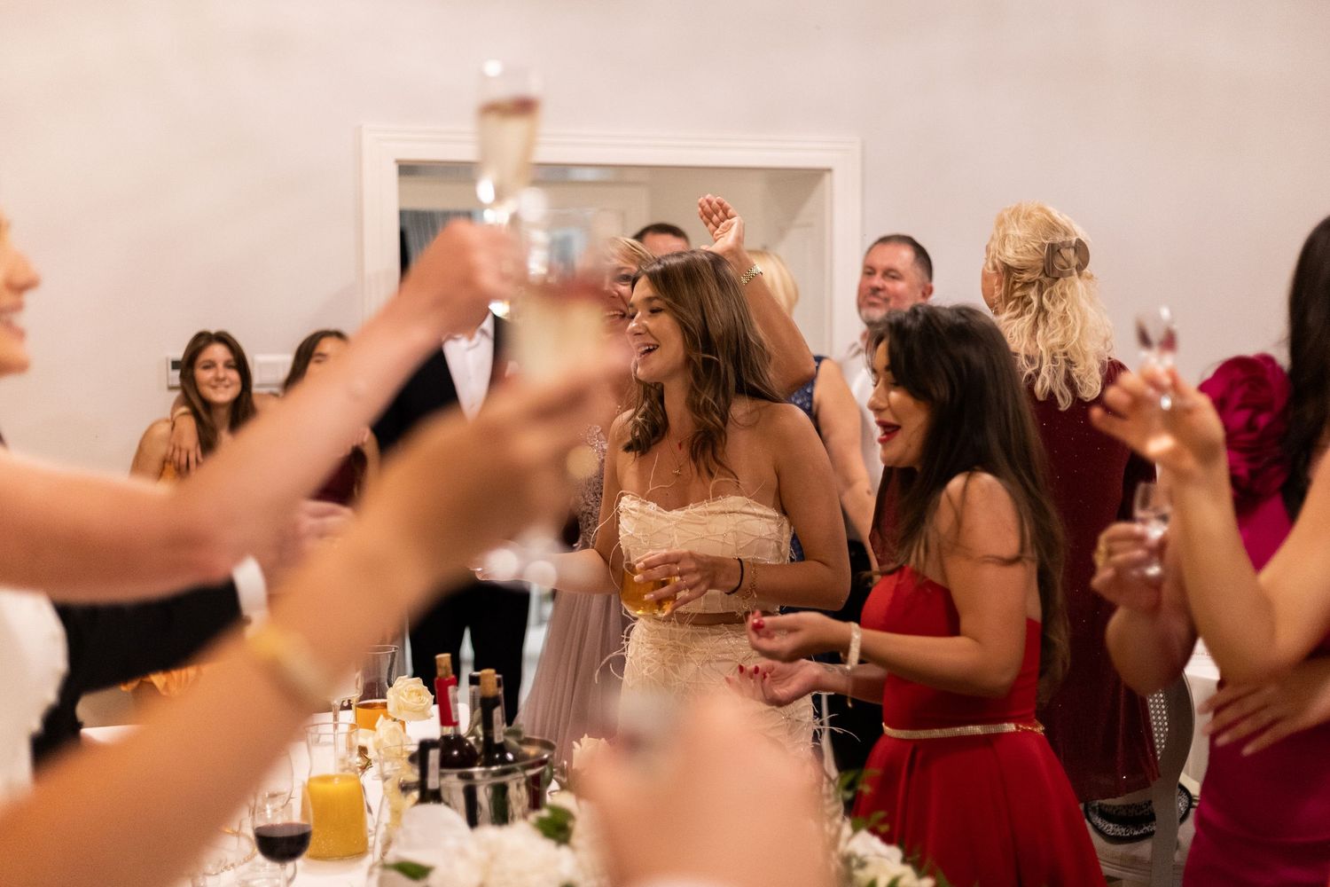 A group of party guests raise their glasses in a celebratory toast during a festive gathering.