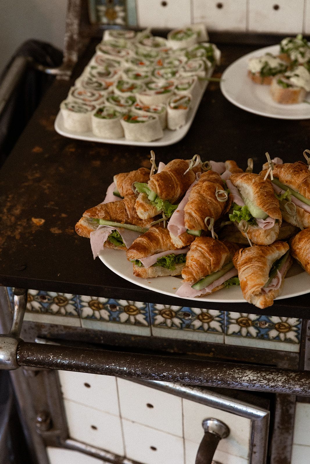 Freshly baked croissant sandwiches with lettuce and fillings arranged on white plates at a catering event.